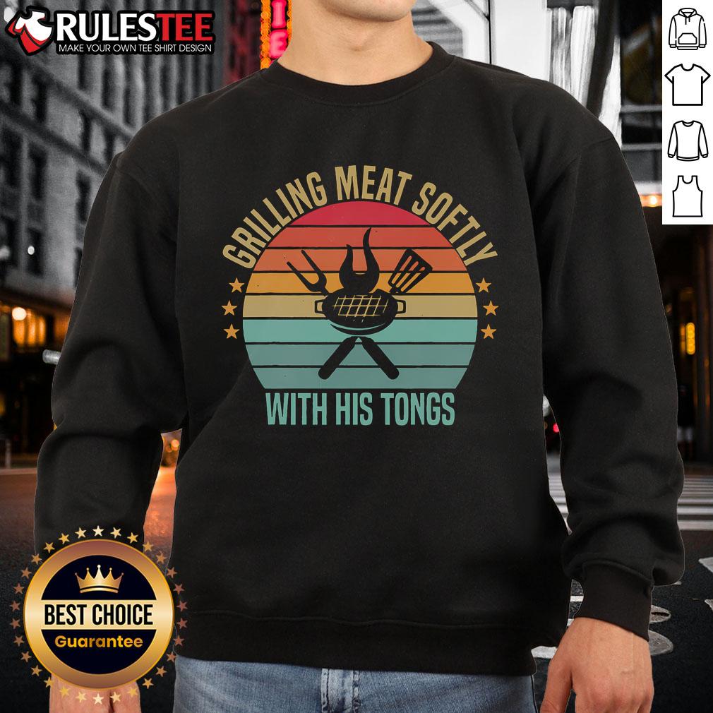 Man grilling meat with tongs in a vintage barbecue sweatshirt, showcasing awesome grilling skills at a backyard cookout.