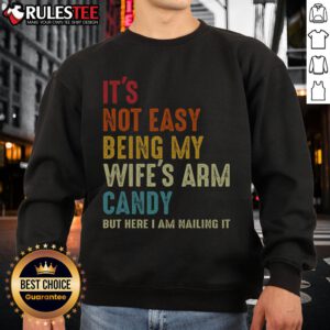 Man wearing 'It's Not Easy Being My Wife's Arm Candy' sweatshirt, showcasing style and humor in casual fashion.
