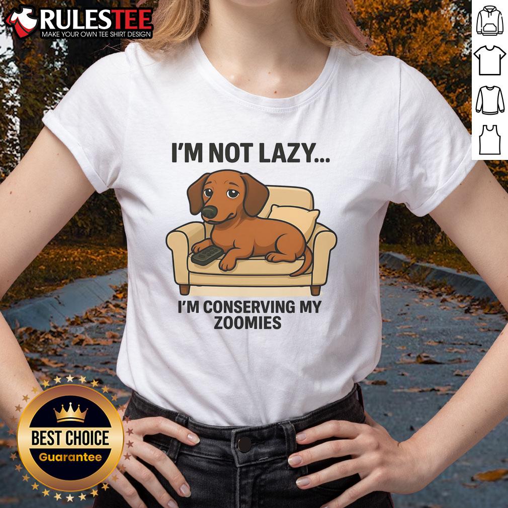 Funny dog lounging with a playful expression, wearing a I'm not lazy, I'm conserving my zoomies tee. Perfect for pet lovers!