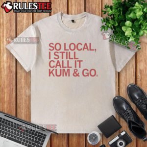 Good-So-Local-I-Still-Call-It-Kum-And-Go washed t-shirt displayed on a wooden surface with a casual styling.