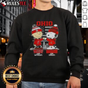 Alt Text: Happy Charlie Brown in Ohio State Buckeyes sweatshirt and Snoopy in Cleveland Browns sweatshirt against skyline.